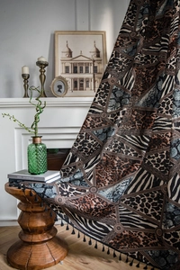 Detail of bohemian geometric print curtain with leopard patterns and black tassel edges