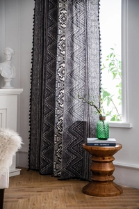 Detail of bohemian black geometric print curtain with stylish black tassel fringe trim