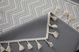 Close-up of gray herringbone faux linen tablecloth with elegant cream fringe details