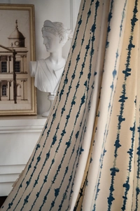 Détail du tissu de rideau beige avec motifs à pois bleus et drapé élégant et fluide