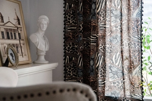 Detail of bohemian leopard print curtains with black pompom fringe and thick cotton fabric