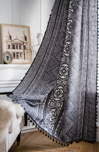 Detail of bohemian curtain with black geometric patterns and delicate fringe trim