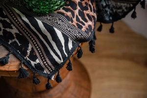 Detail of bohemian leopard print fabric with geometric patterns and fringe tassels