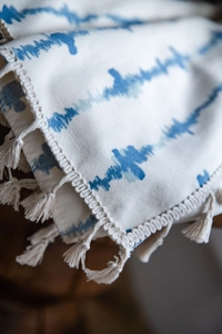 Détail du rideau à motif vagues tie-dye bleu avec dentelle crochetée et pompons