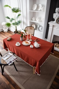 Detail einer dunkelroten Tischdecke mit weißem Bommel-Spitzensaum für Festdekoration