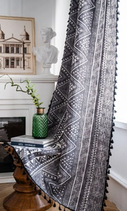 Detail of bohemian black and white geometric print curtain with stylish black pompom fringe