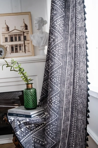 Detail view of Bohemian style dark grey curtains with geometric patterns and black tassels