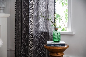 Detail of bohemian curtain with black geometric patterns and elegant tassel trim accents