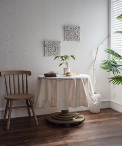 Detail of white ruffled tablecloth with soft pleats on a round vintage wooden dining table