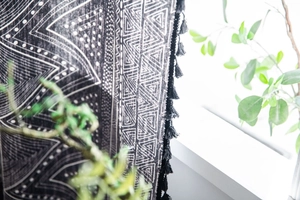 Close-up of black bohemian curtain fabric with white geometric prints and black tassels