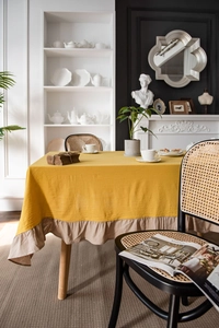 Close-up of ginger yellow cotton tablecloth featuring elegant beige ruffled edge details