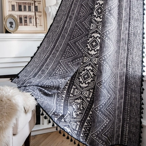 Bohemian black and white geometric pattern curtain with decorative tassels in a home setting