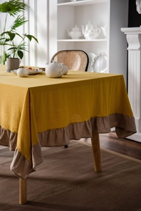 Close-up of mustard yellow tablecloth with light brown ruffled edge in a cozy home setting