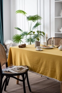 Detailed texture of yellow cotton linen tablecloth with white pom pom fringe edge