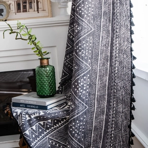 Bohemian black geometric print curtain with fringe tassels on a wooden stool