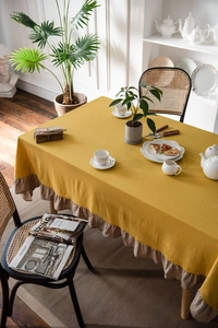 Detail of yellow washed cotton tablecloth showing ruffled edges and natural fabric texture