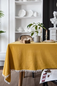 Detailed texture of yellow cotton table cloth with white pom-pom fringe and home decor