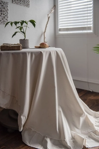 Detail of elegant ruffled edges on creamy white washed cotton tablecloth for round tables
