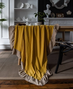 Detailed close-up of yellow ruffled tablecloth with cream frills on a vintage table