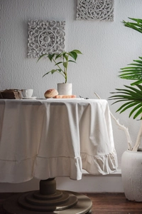 Detail of white ruffled tablecloth with natural cotton texture on a round dining table