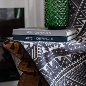 Bohemian black and white geometric printed curtain with tassel fringe on a wooden stool
