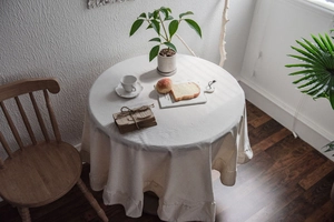 Detailed view of white ruffle edge tablecloth with washed cotton texture in a cozy setting