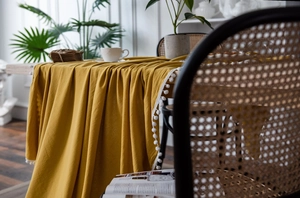 Close-up of mustard yellow tablecloth with white pom-pom trim and premium cotton texture