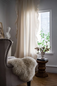 Detailed texture of white linen curtains featuring double French ruffles and natural lighting