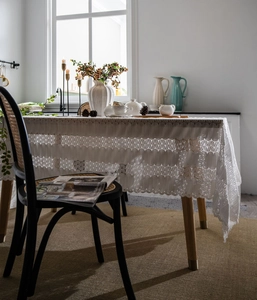 Detail of white vintage lace tablecloth featuring elegant wavy patterns and hollow mesh texture