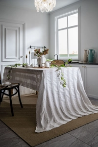Detail of white French lace tablecloth showing intricate floral knitting and scalloped edges