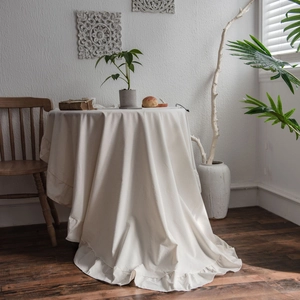 Elegant off-white round tablecloth with ruffled edges in a minimalist cozy home setting