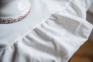 Detail of white cotton linen curtain with elegant ruffled edges and rustic texture