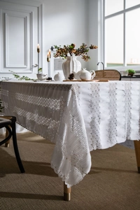 Detailed close-up of white vintage lace tablecloth with intricate floral embroidery