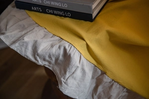 Dettaglio di tenda in tessuto giallo con volant grigi e trama di lino rustico