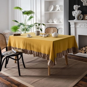 Yellow washed cotton tablecloth with ruffled edges on a rectangular table in a home setting