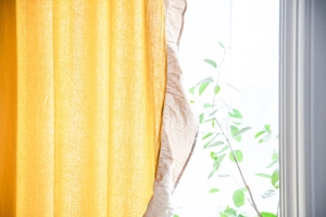 Dettaglio della tenda da caffè in lino giallo con bordi a balze e luce naturale