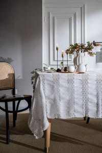 Detail of white lace tablecloth featuring textured floral crochet and wavy hollow-out edges