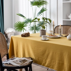 Elegant yellow cotton tablecloth with white pom-pom fringe in a cozy home dining setting