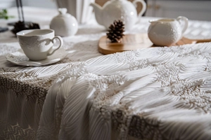 Close-up of white 3D textured lace tablecloth with hollow patterns for table decor