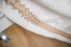 Vue détaillée du tissu en lin beige avec bordure en dentelle au crochet marron fait main