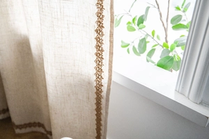 Vue détaillée du rideau en lin beige avec bordure en dentelle géométrique marron foncé