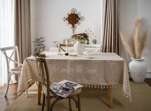 Detail of linen texture tablecloth with elegant tassel edges in a warm beige tone