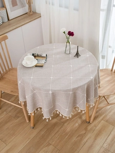 Detail of round gray plaid tablecloth with white cotton tassels for home dining decor