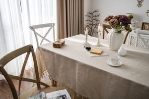 Detailed close-up of beige linen tablecloth featuring elegant tassel edges and natural texture