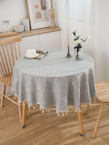 Close-up of a grey checkered round tablecloth with elegant white fringe tassels