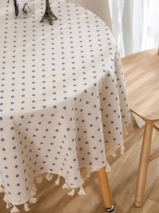 Detail of round cotton linen tablecloth with blue floral print and beige fringe trim