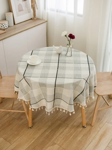 Detailed view of the light grey plaid round tablecloth with elegant beige fringe trim edges