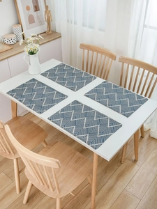 Close-up of four rectangular navy blue wave jacquard placemats on a white dining table