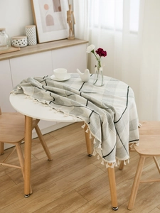 Close-up of linen-style checkered tablecloth with elegant white tassels on a round table