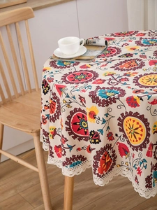 Detail of bohemian round tablecloth with colorful floral print and white lace trim edge